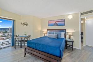 a bedroom with a blue bed and a balcony at Executive Center 1604 in Honolulu