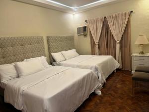 two beds in a hotel room with white sheets at Fuji sleeps 16-18 in Angeles
