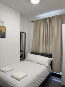 a bedroom with a bed with white sheets and a window at 18 Budget Inn in London