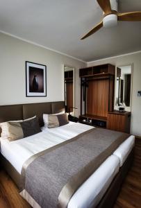 a bedroom with a large bed with a ceiling fan at Hotel Italia in Munich +84 photos