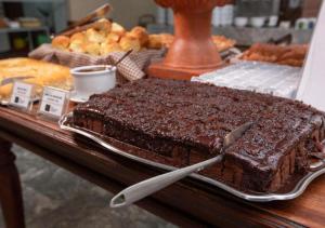 a table with a tray of chocolate cake and bread at Rede Andrade Royal in Itabuna