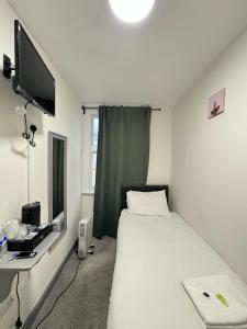 a bedroom with a bed and a desk and a television at 18 Budget Inn in London
