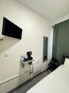 a hotel room with a bed and a tv on the wall at 18 Budget Inn in London