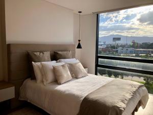 a bedroom with a large bed with a large window at GV Aparta Suites - Centro Chía in Chía
