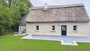an old house with a thatched roof and a yard at Patricks Thatch Cottage in Oranmore