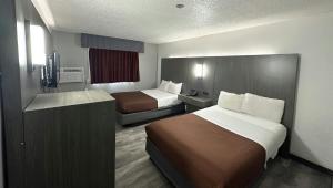 a small hotel room with two beds and a television at Magnuson Hotel Fort Wayne North - Coliseum in Fort Wayne