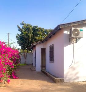 a white building with pink flowers in front of it at Zen villa in Old Yundum