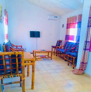 a room with chairs and a table and a television at Zen villa in Old Yundum