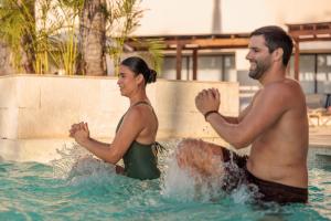 a man and a woman in a swimming pool at Dreams Aventuras Riviera Maya - All Inclusive in Puerto Aventuras