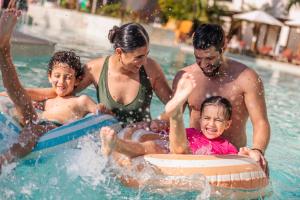 a family playing in the water in a pool at Dreams Aventuras Riviera Maya - All Inclusive in Puerto Aventuras