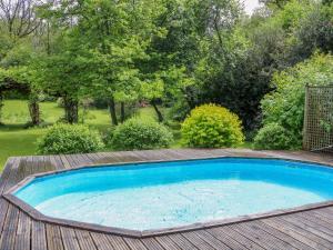 a swimming pool on a deck with a wooden floor and trees at Petworth Barn in Petworth