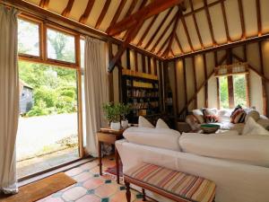 a living room with white couches and a large window at Petworth Barn in Petworth