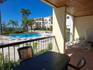 a balcony with a table and chairs and a swimming pool at Clube Alvor Ria - Waterfront luxury apartments with stunning views in Alvor