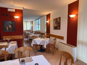 a restaurant with white tables and chairs and red walls at Albergo Lario in Gera Lario