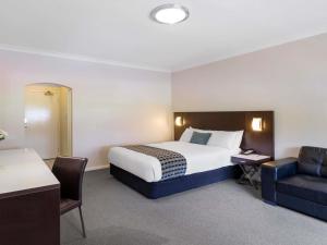a hotel room with a bed and a desk and a chair at Mercure Wagga Wagga in Wagga Wagga