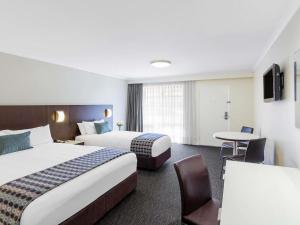a hotel room with two beds and a table at Mercure Wagga Wagga in Wagga Wagga