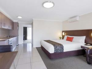 a hotel room with a bed and a kitchen at Mercure Wagga Wagga in Wagga Wagga