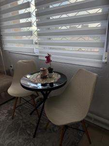a table with two chairs and a table with a flower on it at Apartman Rejjan in Zenica
