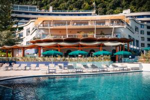 a pool with chairs and umbrellas in front of a building at Hilton Sorrento Palace in Sorrento