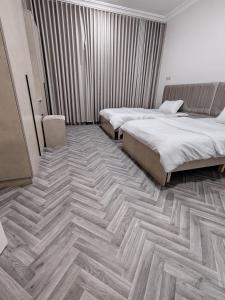 a bedroom with two beds and a wooden floor at Sukoon Buraydah سكون بريدة in Buraydah