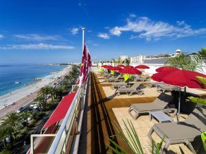 a balcony with chairs and umbrellas and the beach at Aparthotel Adagio Nice Promenade des Anglais in Nice