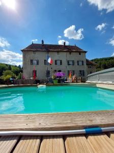 a large swimming pool with a house in the background at Domaine de Fontenelay in Gézier-et-Fontenelay
