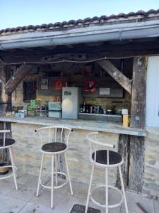 three bar stools sitting at a counter with a refrigerator at Domaine de Fontenelay in Gézier-et-Fontenelay