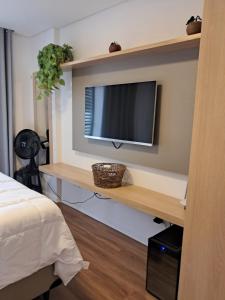 a room with a tv on a wall with a shelf at Grand Reserva Granja Brasil in Araras Petropolis