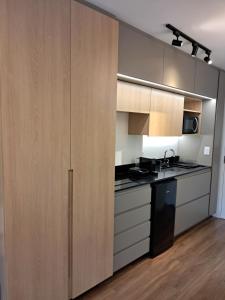 a kitchen with wooden cabinets and a black appliances at Grand Reserva Granja Brasil in Araras Petropolis