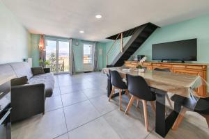 a living room with a table with chairs and a tv at Gites Bretzel Cigogne ET Manala in Munwiller