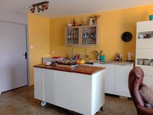 a kitchen with a white island in a room at Au jeu de mots, chambre d'hôtes proche Poligny in Barretaine +2 photos