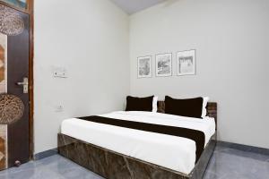 a bedroom with a large white bed with black pillows at Hotel O Kalka in Faridabad +20 photos