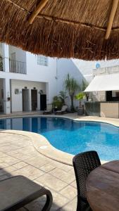 a swimming pool with a table and a straw umbrella at Hotel María Jose in Mérida