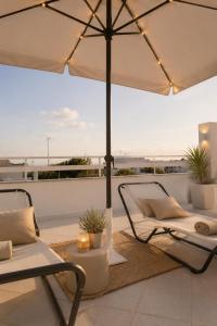 a patio with an umbrella and chairs on a roof at Poésia in San Foca
