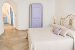 a white bedroom with a bed and a blue door at Maridea - Il Paradiso sulla Baia in Ponza