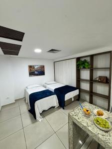 a hotel room with two beds and a table at Praiano Flat Tambaú in João Pessoa