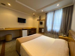 a hotel room with a bed and a flat screen tv at Saionara Hotel in Rio de Janeiro