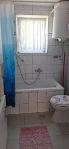 a bathroom with a tub and a toilet and a window at Apartman Villy 2 in Jadranovo