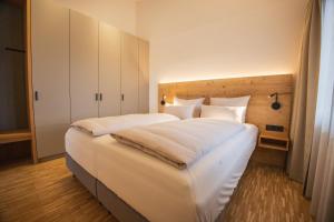 a bedroom with a large bed with white sheets at Alpensonne Apartments in Bad Wiessee +13 photos