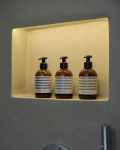 three bottles of soap on a shelf in a bathroom at Amorgina in Amorgos +84 photos