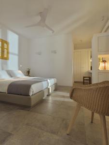a white bedroom with a bed and a chair at Amorgina in Amorgos