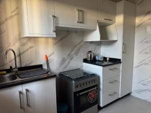 a small kitchen with white cabinets and a stove at Flora House in Maputo +6 photos