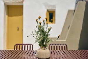 a vase with yellow flowers sitting on a table at Amorgina in Amorgos