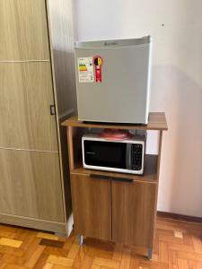 a microwave sitting on top of a wooden stand at Suite Privativa in Dom Pedrito