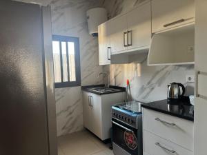 a small kitchen with white cabinets and a stove at Flora House in Maputo