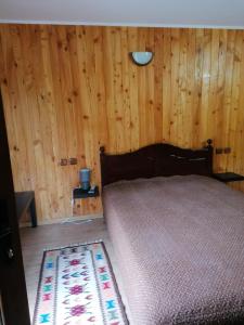 a bedroom with a bed and a wooden wall at La Păstrăvărie ,,Casa Iov,, in Moroeni +41 photos