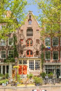 a large brick building with windows and trees at The Orange Canals Suite in Amsterdam