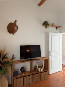 a living room with a flat screen tv on a wooden entertainment center at Le Gahignon in Lanton