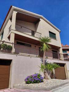a building with a palm tree in front of it at A casa de Aliciña in Sanxenxo