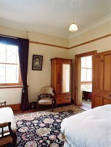 a bedroom with a bed and a chair and windows at Braemar On Parliament St in Auckland